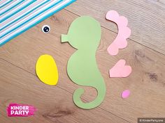 paper cut out of the shape of a seahorse on a wooden floor with scissors