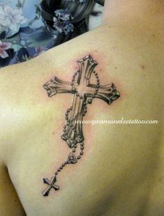 a cross tattoo on the back of a woman's shoulder