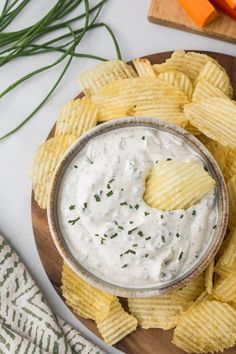 a wooden plate topped with chips and dip