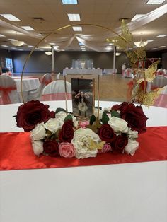 the centerpiece is adorned with red and white flowers on a table in a banquet hall