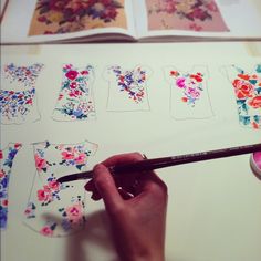 someone is doing something with flowers on the paper and using a paintbrush to draw them