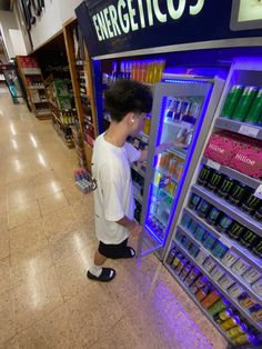 a young boy is looking at an energy drink vending machine in a grocery store