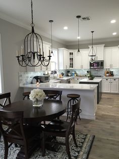 a dining room table and chairs in front of a large kitchen island with an oven