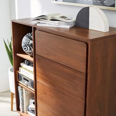 a wooden dresser with books and magazines on it