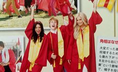 three girls in graduation gowns holding up flags