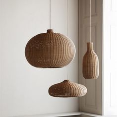 three wicker lamps hanging from the ceiling next to a window in a white room