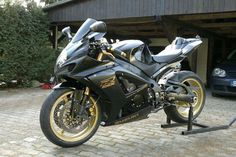 a black and gold motorcycle parked in front of a garage