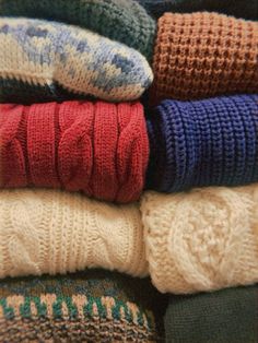 several knitted sweaters stacked on top of each other in different colors and patterns