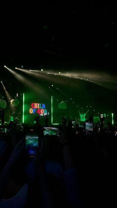 people taking pictures on their cell phones at a concert with lights and sound equipment in the background