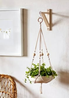 a potted plant hanging from a hook on a wall next to a wicker chair