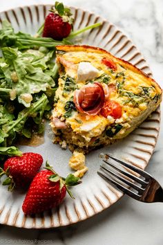 an omelet with spinach and strawberries is on a plate next to a salad