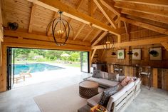 a living room filled with furniture next to a swimming pool in a wooden building surrounded by greenery