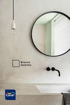 a bathroom sink sitting under a round mirror next to a wall mounted faucet