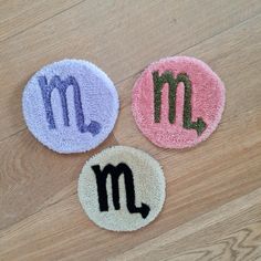 three bath mats with the letter m and m in different colors on a wooden floor