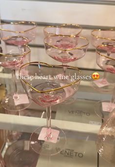 several wine glasses are on display in a glass case with gold rims and hearts