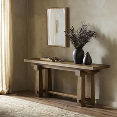 a wooden table with two vases sitting on top of it next to a mirror