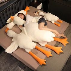 a woman laying on top of a bed covered in giant stuffed ducks and ducklings