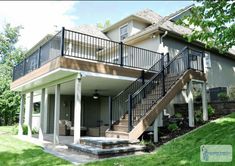 a house with stairs leading up to the front door and second story deck area on top of it