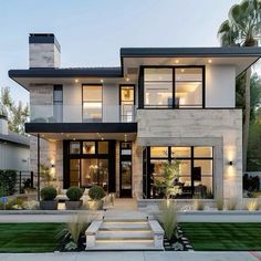 a large modern house with lots of windows and plants in front of the entrance to it