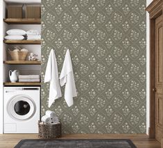 a washer, dryer and towels in a small room with wallpaper on the walls