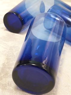 two blue glass vases sitting on top of a white tablecloth covered flooring