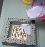 someone is pouring something out of a cup on top of some legos that are sitting on a table