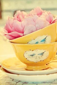 two yellow tea cups with pink flowers in them