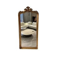 a large gold framed mirror sitting on top of a white floor next to a couch