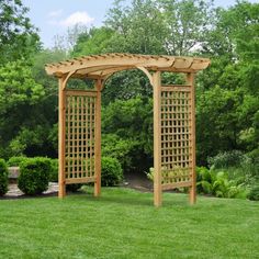 a large wooden arbor in the middle of a grassy area with trees and bushes behind it