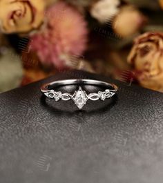 a diamond ring sitting on top of a black surface next to flowers and roses in the background