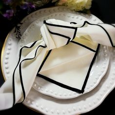 a white plate topped with two napkins on top of each other next to flowers