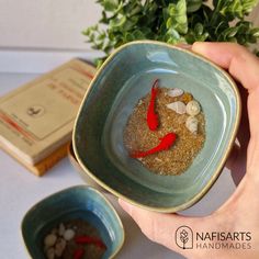 a person holding a bowl filled with sand and fish