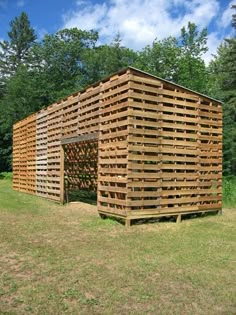 a building made out of wooden pallets sitting on top of a grass covered field