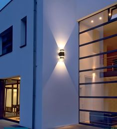 an exterior view of a modern house with lights on the outside wall and in the front door