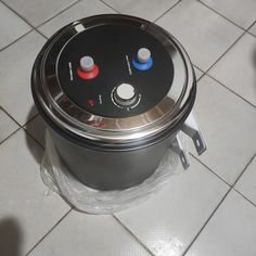 an electric cooker sitting on top of a white tiled floor