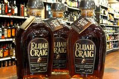 three bottles of eliah craig sit on a counter in a liquor store