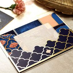 the wedding card is decorated with blue and gold paper, along with a pink flower