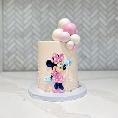 a minnie mouse cake with pink and white balloons