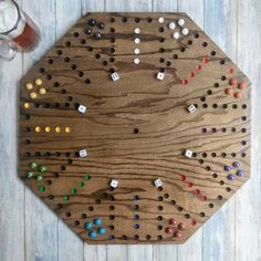 a wooden board with several different colored dots on it and a glass of beer next to it