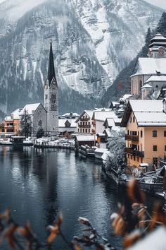 an alpine town is covered in snow and surrounded by mountains, with a river running through it