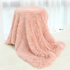 a fluffy pink blanket sitting on top of a white floor