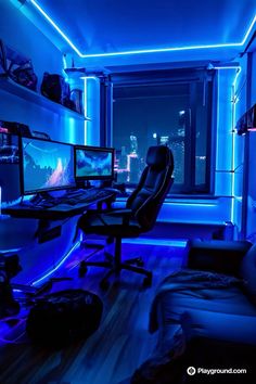 a room with two computer monitors, a chair and a couch in it at night