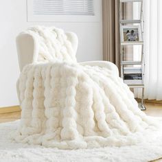 a white chair sitting on top of a rug covered in a pile of fluffy blankets