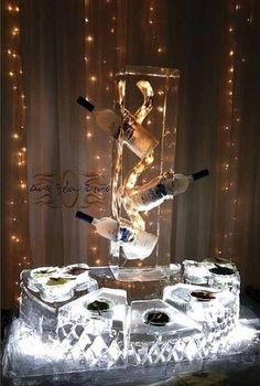 an ice sculpture with wine bottles in it and lights around the base, on display