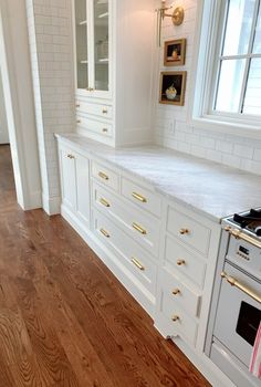 a kitchen with white cabinets and wood flooring, along with a stove top oven