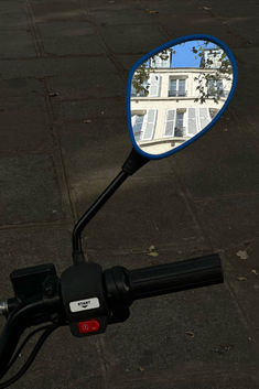 a close up of a motorcycle mirror with a building in the background