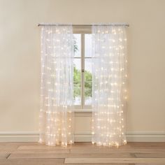 a white curtain with lights hanging from it in front of a window