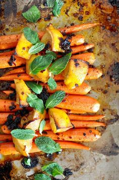 carrots and other vegetables on a baking sheet with minty garnishes