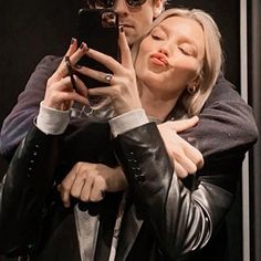 a man and woman taking a selfie with their cell phones in front of them