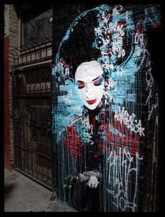 a painting on the side of a building that has graffiti all over it and features a woman's face